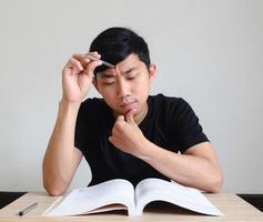 Man serious face with test,Young man sit at the desk and think with the book on table,Test concept photo