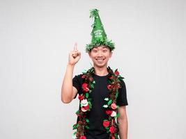 Portrait young man happy face with green hat and tassel colorful point finger above look at camera and smile on white isolated background photo