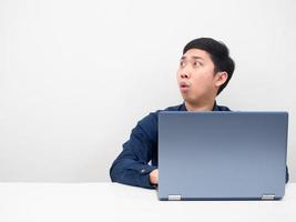 Man sitting with laptop on the table looking at copy space feeling shocked photo