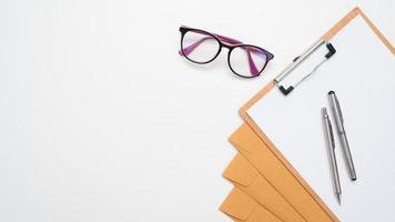 Pen on document envelope and board and glasses on the table top view copy space photo