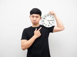 El hombre señala con el dedo el reloj analógico una emoción seria fondo blanco. foto