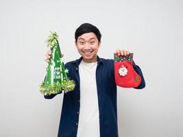 hombre asiático alegre sosteniendo calcetín de navidad y sombrero verde fondo blanco foto