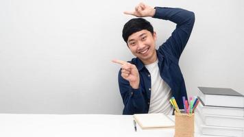 Man sit at the desk smiling gesture point finger at copy space photo