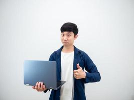 hombre guapo asiático sosteniendo una computadora portátil mostrar pulgar hacia arriba cara segura sobre fondo de pared blanca foto