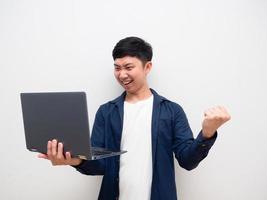 Asian man look at laptop in hand and feel happy show fist up happy smile on white isolated photo