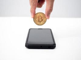 Close up hand pick up bitcoin out of smart phone,Digital money concept photo