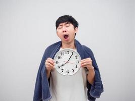 Sleepy man yawn show clock in his hand and cover body by towel on white background photo