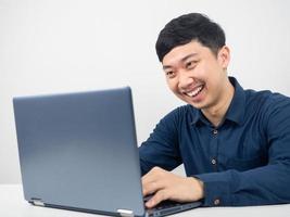 hombre sentado y usando una laptop para trabajar con emoción feliz, empleado masculino trabajando con una laptop foto