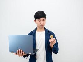 Asian man holding laptop and looking at bitcoin in hand on white background digital money concept photo