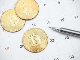 Closeup golden bitcoin and pen on calendar photo