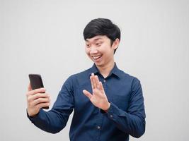 hombre asiático sosteniendo una videollamada de teléfono móvil con emoción feliz y una sonrisa en el fondo blanco foto