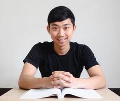 hombre asiático sentarse en el escritorio y el libro feliz sonrisa cara fondo blanco foto