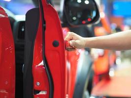 Hand opening the door of car red color event background photo