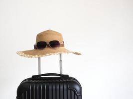 Closeup retro hat with sunglasses above luggage on white isolated space holiday and travel concept photo