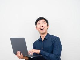 Man holding laptop feeling excited looking up at copy space photo