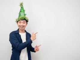 Cheerful man wearing green hat point finger at copy space photo