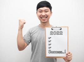 Man smiling showing document wood board with 2022 message and check list sucess first up photo