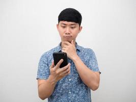 Asian man blue shirt looking at mobile phone gesture thinking photo