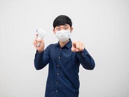 Man wearing mask hodling infrared thermometer point at you on white background isolated photo