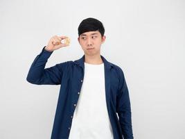 Asian man looking at gold bitcoin in his finger on white isolated background the digital money concept photo