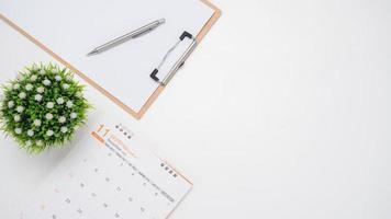 Calendar with vase and document board on white table top view copy space photo