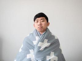 Young man with blanket cover his body and feel bored at face look at camera on white isolated,Don't want to wake up concept photo