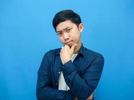 Man gesture serious thinking about something blue background photo