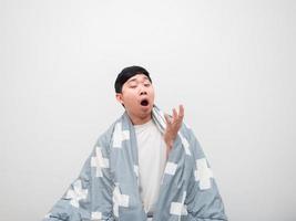 Asian man yawn and cover blanket his body sleepy face on white isolated background photo