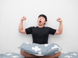 Lazy Man sit on the bed with pillow feeling sleepy and yawn photo