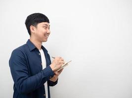 Asian man note in diary book with smiling and looking at copy space side view photo