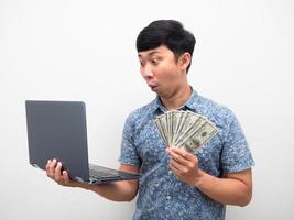 el hombre obtiene dinero con el concepto de trabajo en línea, el hombre emocionado mirando la computadora portátil con mucho dinero foto