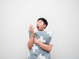 Asian sleepy man yawn and hug pillow on white background lazy concept photo