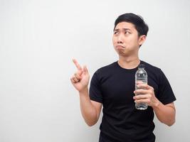 hombre asiático sosteniendo una botella de agua y sintiendo una emoción triste señalar con el dedo el espacio de la copia foto