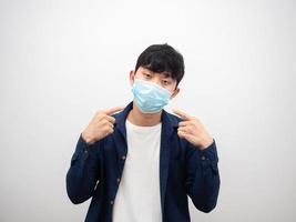 Sick man feel bad point finger at protect mask at his face on white background photo