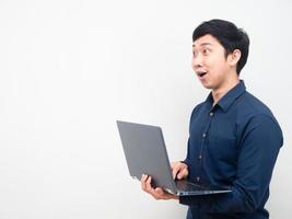 hombre que sostiene la computadora portátil sintiéndose asombrado mirando el espacio de la copia foto