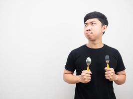 Man hungry holding cutlery and looking at copy space photo