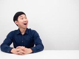 Young man sitting and feeling excited looking at copy space white background photo