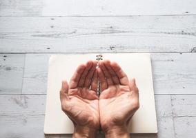 concepto de paz de la mano rezando con la página en blanco del libro abierto en la vista superior blanca de madera foto