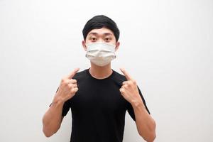 Asian man point finger at protect mask on his face portrait white background photo