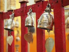 Gold bell hanging at red fence in temple for lucky believe of buddhism in Thailand at Chiangmai February 2019. photo