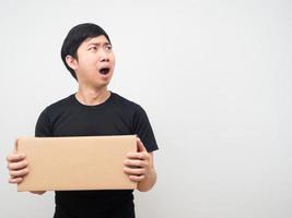 Asian man feeling shocked and holding box in hand and looking at copy space photo