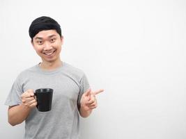 Man holding coffee cup with smiling and point finger at copy space photo