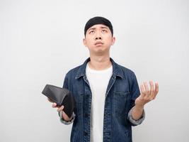 Asian man feeling sad about no money holding wallet in hand looking up photo