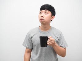hombre insomne sosteniendo una taza de café mirando hacia arriba, el hombre se despierta por la mañana con sueño foto