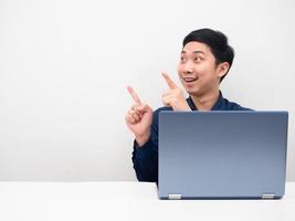 hombre asiático con sonrisa de portátil y señalar con el dedo el fondo blanco del espacio de copia foto
