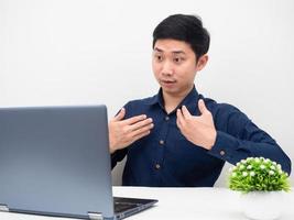 el gesto del hombre explica su trabajo en línea con una laptop en el fondo blanco de la mesa foto