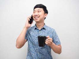 hombre alegre sonriendo sosteniendo una taza de café y hablando con un retrato de teléfono móvil foto