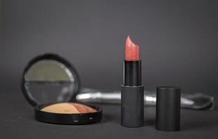 Red lipstick with an open cap on a dark gray background photo