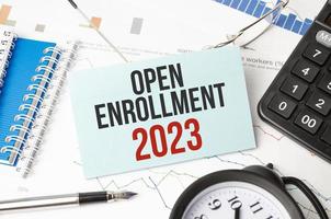 OPEN ENROLLMENT 2023 words on charts with alarm clock and calculator photo