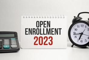 OPEN ENROLLMENT 2023 words with calculator and clock with notebook photo